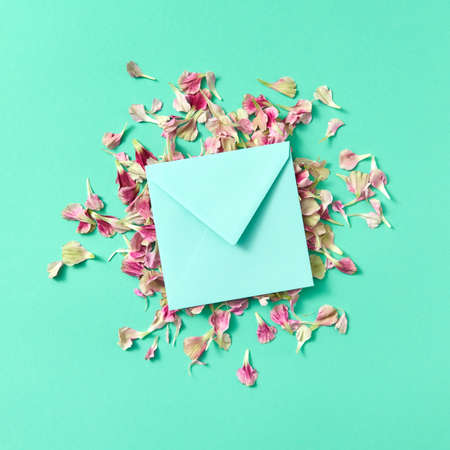 Mock up craft envelope with floral petals on a turquoisebackground.の写真素材