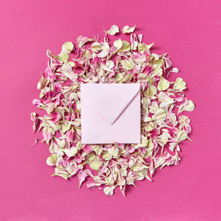 Mockup handmade envelope on a round frame from petals on a magenta background.の写真素材