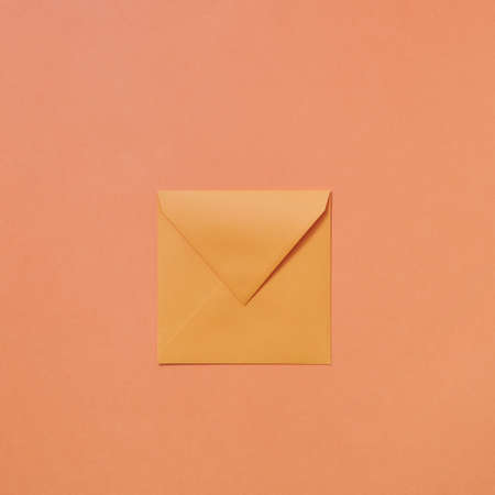 Empty handmade mock up envelope on a peach color background .の写真素材