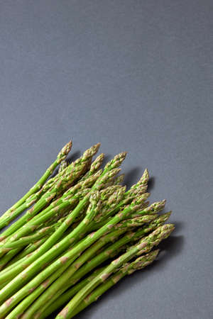 Pile of green organic asparagus on a grey background.の写真素材