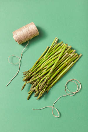 Bunch of natural healthy asparagus and a coil of rope on a green background.の写真素材
