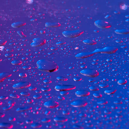 Water drops background highlighted with ultraviolet.の写真素材