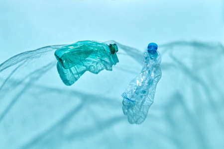 Ocean waves from shadows of polyethylene foil with floating bottles underwater on a pastel blue background, copy space. Concept of enviromental pollution of world ocean.の写真素材