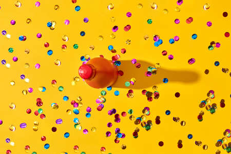 Holiday background with red painted bottle and colored confetti.の写真素材