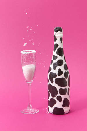 White powder falls in a glass and painted black spots wine bottle.の写真素材