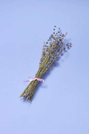 Decorative corsage from natural dry lavender flowers on the same color background with soft shadows, place for text. Creeting card.の写真素材