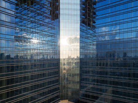 Aerial shot of modern office building windows, reflection of cityscape on a sunny day.