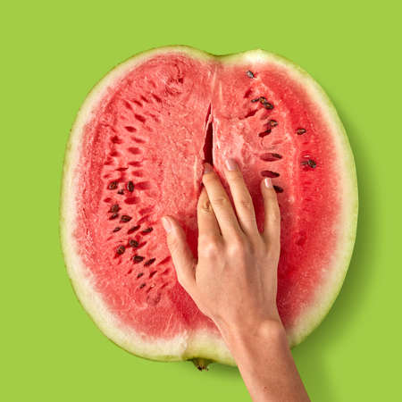 Womans finger touch inside watermelon ripe juicy fruit.の写真素材