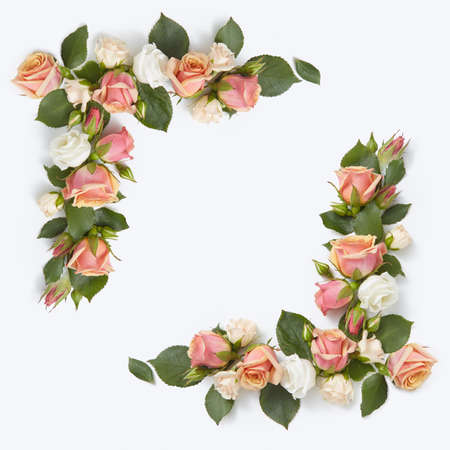 Romantic congratulation corner frame from roses flowers with green leaves on a light grey background, copy space. Flat lay.の写真素材