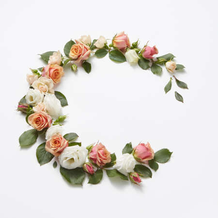 Decoration in the form of corner wreath from beautiful roses flowers with green leaves on a light grey background, copy space. Congratulation card for birthday.の写真素材