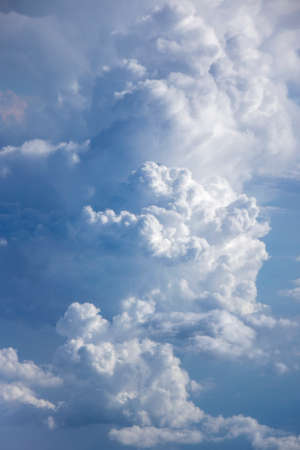 Vast blue sky with big white fluffy clouds lighted sun.の写真素材
