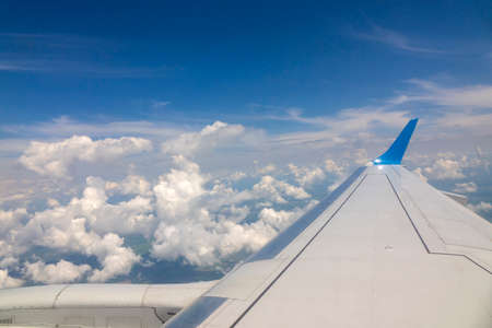 Wing of the plane on blue sky cloudy background.の写真素材