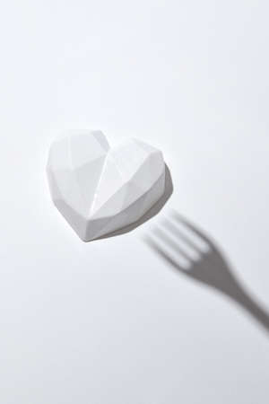 White plaster heart with hard shadow from fork.の写真素材