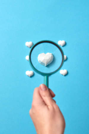 Focused plaster heart in a magnifying glass in the hand.の写真素材