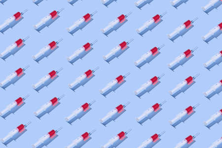 Medical pattern with plastic syringes of red vaccine.