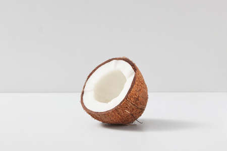 Natural organic tropical fruit half of ripe coconut on a light grey duotone background, copy space. Vegetarian concept.の写真素材