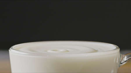 Milk drops drip into a cup with organic milk making splash around a dark background.の写真素材