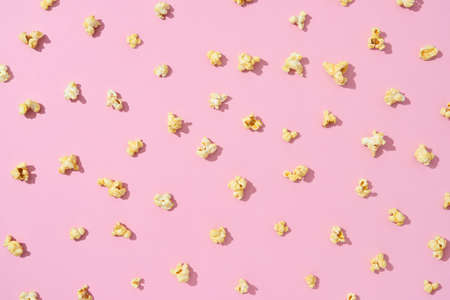 Popular snack for entertaiment and watching movies popcorn pattern of salt or sweet taste on a light pink background with hard shadows. Flat lay.の写真素材