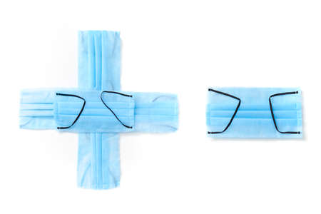 Symbol plus and minus handmade from medical antibacterial protective blue face masks on a white...