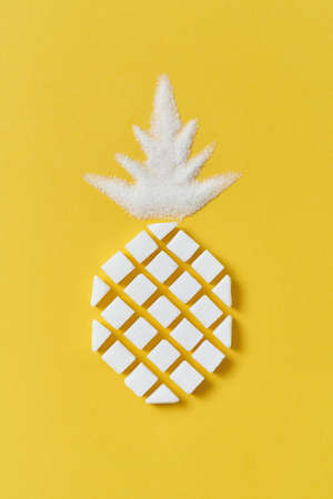 Exotic fruits composition creative pineapple handmade from rafined anf granulated sweet sugar on a yellow background with copy space. Flat lay.の写真素材