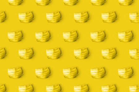 Yellow painted protective medical masks on the same color background.の写真素材