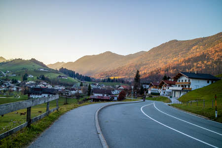 Beautiful landscape with asphalt road through the traditional country in Austria on a background of mountains and clear blue sky in a sunny day.の写真素材