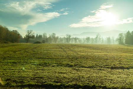 Beautiful rural morning scape with green fields, areas and trees on a background of sunny sky in autumn time, Austria.の写真素材