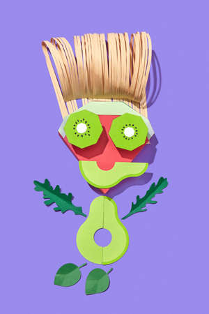 Handmade from colorful paper little man made from papercraft fruits and vegetables on a purple background with shadows, copy space. Vegan healthy food.の写真素材