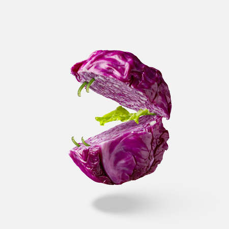 Flying cut fresh natural organic red cabbage in the shape of mouth with teeth and tongue from green lettuce leaves above white background, copy space.の写真素材