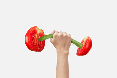Creative sport barbell made from freshly picked natural organic cut tomatoes on green stick in a woman's hand against white background, copy space. Healthy lifestyle concept.の写真素材