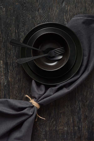 Served kitchen table with cookware and textile napkin in black colors.の写真素材
