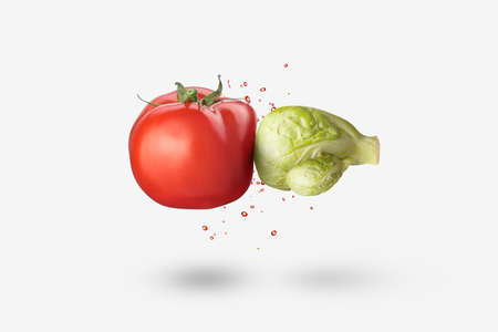 Creative vegan composition from fresh natural organic cabbage in the shape of boxing glove punching red tomato vegetable with splash on a white background, copy space. Vegan healthy food concept.の写真素材