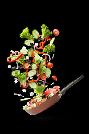 Frying pan with falling vegetablesの写真素材