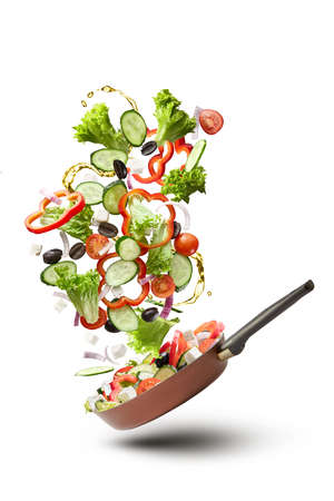 Frying pan with falling tasty fresh vegetablesの写真素材