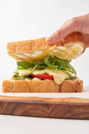 Person removing toast off sandwich with vegetables