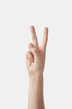 Victory gesturing female or V letter hand on white.の写真素材