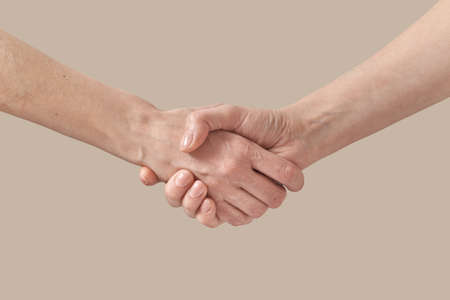 Two female hands handshake on beige.の写真素材