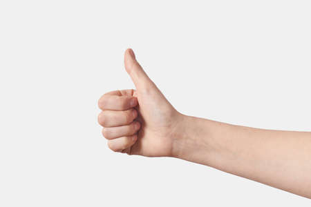 Thumb up female gesturing hand on white.の写真素材