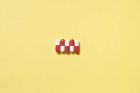 Pharmaceutical capsules over yellow backdrop.の写真素材