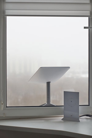 KYIV, UKRAINE - JANUARY 24, 2023: Starlink antenna and wi-fi router on windowsill in home interior.のeditorial素材