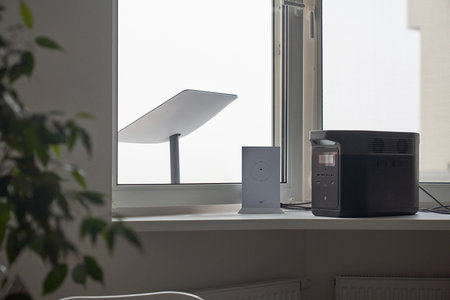 KYIV, UKRAINE - JANUARY 24, 2023: Starlink antenna behind window, wi-fi router and Ecoflow generator on windowsill in cozy home interior.のeditorial素材