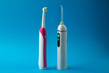 Toothbrush and irrigator with a floss cartridge on a blue pastel background with copy space, close up viewの写真素材