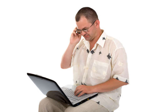Man typing on the keyboard of laptop and speaking on cell phoneの写真素材