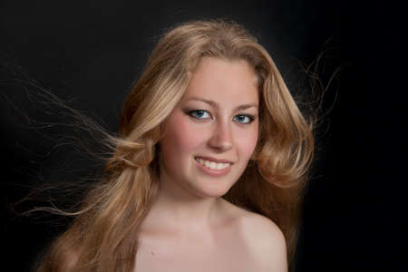 Young blond girl with fly-away hair on dark backgroundの写真素材