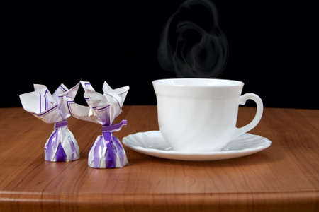 Cup of coffee and chocolate candy on wooden table.の写真素材