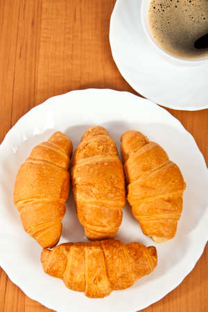 Newly-baked croissants and cup of coffee on wooden table.の写真素材