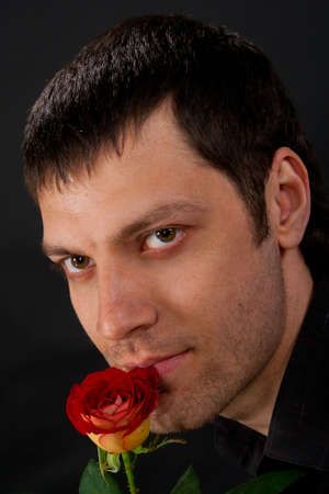 Portrait of handsome man with rose on dark background.の写真素材