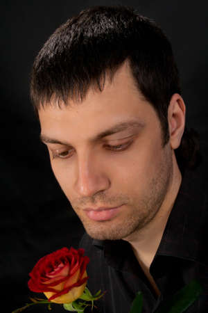 Portrait of handsome man with rose on dark background.の写真素材