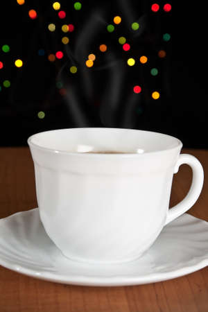 Cup of coffee on wooden table with many-colored sparkles の写真素材