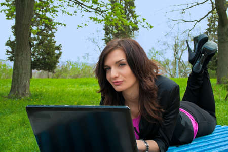 Young woman is working on laptop on a park benchの写真素材
